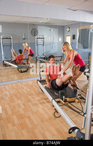 Jeune couple sur Pilates équipement d'exercice dans la salle de sport Banque D'Images