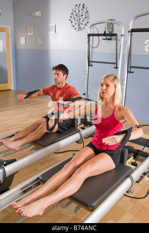 Young couple working out sur l'équipement d'exercice de Pilates en salle de sport Banque D'Images