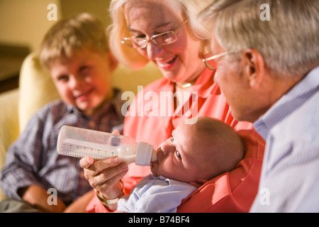 Grand-mère nourrir bébé tout en petit-fils et son grand-père watch Banque D'Images