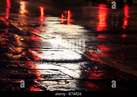 Route mouillée vide avec des lumières dans la ville la nuit Banque D'Images