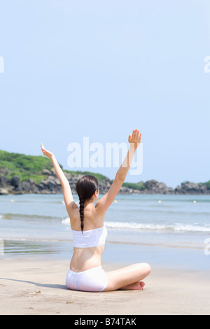 Young woman sitting on beach Banque D'Images