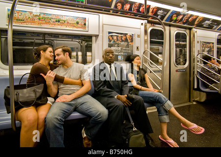 Inconscients de leur environnement un couple est ouvertement affectueux dans un wagon de métro de la ville de New York comme d'autres passagers les ignorer Banque D'Images