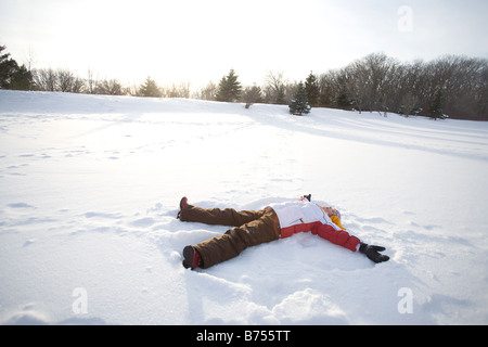 9 ans couché sur la neige, faire de la neige ange, Winnipeg, Canada Banque D'Images