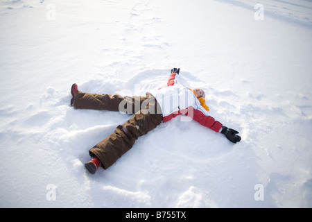 9 ans couché sur la neige, faire de la neige ange, Winnipeg, Canada Banque D'Images