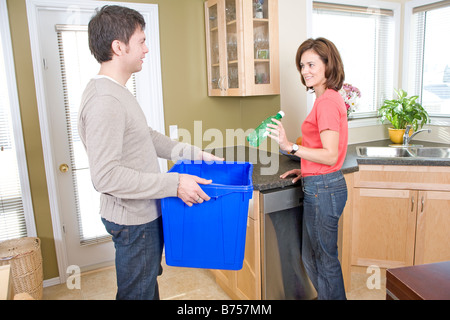 Couple in kitchen, woman putting bouteille en plastique dans le bac de recyclage, Winnipeg, Canada Banque D'Images