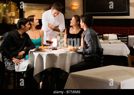 Deux couples avec un garçon de cuisine dans un restaurant Banque D'Images