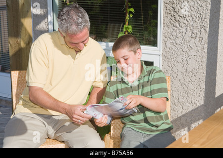 Père et fils à la recherche de magazine, assis sur le pont, Winnipeg, Canada Banque D'Images