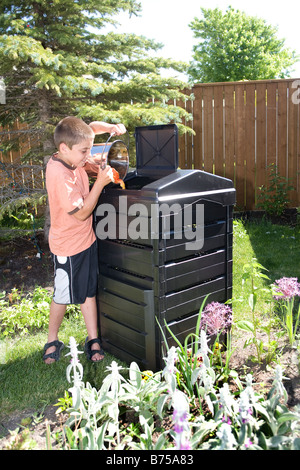 Garçon avec seau de compost composteur à côté dans la cour, Winnipeg, Manitoba, Canada Banque D'Images