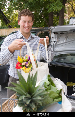 Jeune homme loading provisions dans des sacs en tissu, en voiture, Winnipeg, Manitoba, Canada Banque D'Images