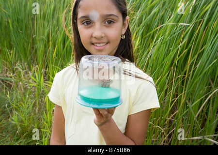 Fille de 8 ans dans des milieux humides holding grenouille dans récipient collecteur, Winnipeg, Canada Banque D'Images