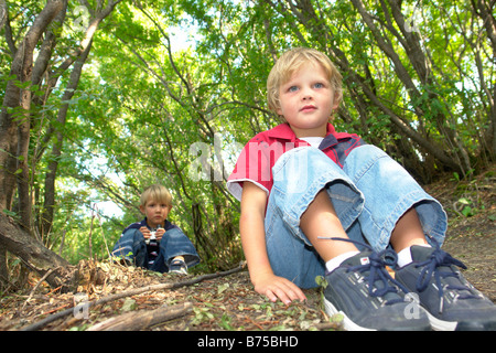 Quatre et six ans frères assis sur un sentier en forêt, Winnipeg, Manitoba, Canada Banque D'Images