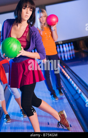 Portrait of a young woman playing bowling avec ses amis Banque D'Images