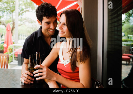 Close-up of a young couple holding beer bottles and smiling Banque D'Images