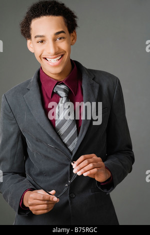 Portrait of a businessman holding his eyeglasses and smiling Banque D'Images