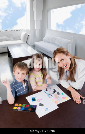 Portrait of a Mid adult woman aider ses enfants en peinture Banque D'Images