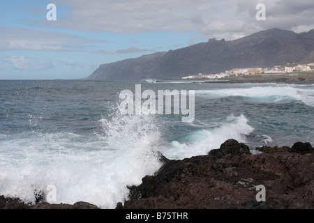 Une vague s'écrase près de Punta Blanca Alcalá pendant une mer avec des falaises de Los Gigantes derrière Tenerife Espagne Banque D'Images