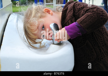 Blanc brillant d'une fontaine d'eau potable et d'un cute blonde toddler Banque D'Images