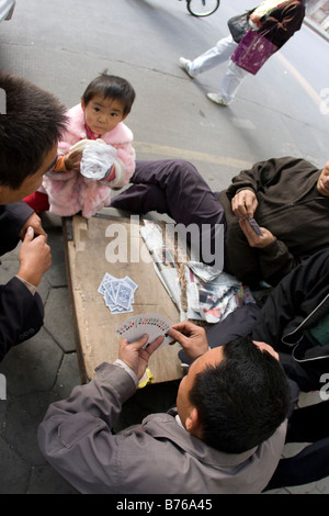 Groupe d'wokers de rue jouer poker chinois avec petite fille dans les rues de la communauté de classe supérieure Banque D'Images