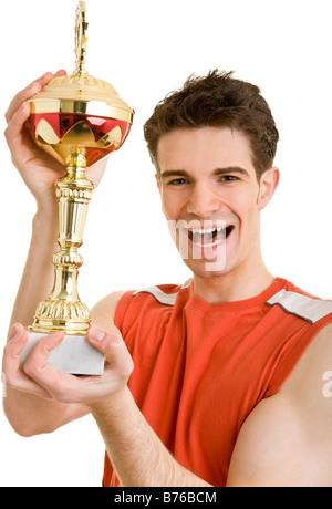 Junger Mann dans jubelnd Sportkleidung hält einen Pokal nach oben Banque D'Images