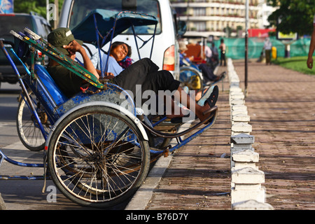 Les conducteurs ayant un cyclo de couchage sieste dans les rues de Phnom Penh, Cambodge Asie du sud-est Banque D'Images