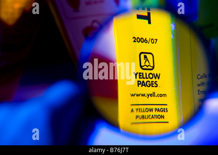 Pages Jaune pris à travers une loupe montrant close up de logo d'entreprise. Banque D'Images