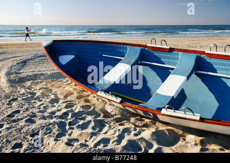 Woman in background walking on beach et petit bateau, New Jersey, USA Banque D'Images