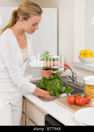 Femme laver les légumes d'un évier de cuisine Banque D'Images