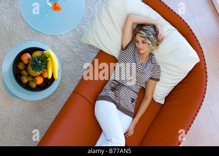 Jolie jeune femme couchée sur un canapé et détend Banque D'Images