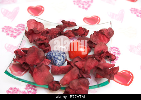 Bol en verre avec des coeurs de pierre et pétales de rose Banque D'Images