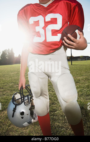 Football player holding helmet et le football sur terrain Banque D'Images