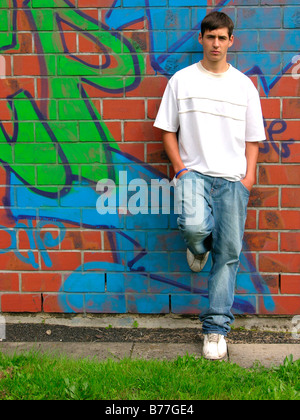 16-year-old adolescent appuyé contre un mur recouvert de graffitis Banque D'Images