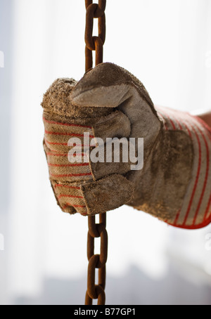 Close up of gloved hand holding chain Banque D'Images