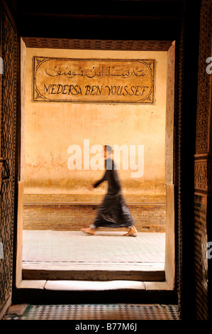 Homme portant une cape marcher dans une ruelle à la madrasa Ben Youssef, Qur'an, l'école dans la médina de Marrakech, Mo Banque D'Images