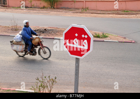 L'homme sur un cyclomoteur, panneau d'arrêt en arabe, Marrakech, Maroc, Afrique Banque D'Images