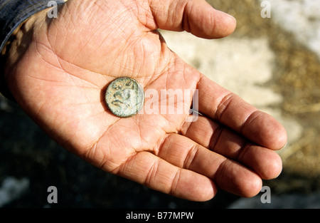 Pièce de monnaie romaine dans la main d'un black marketeer, Apamée, en Syrie, au Moyen-Orient, Orient Banque D'Images