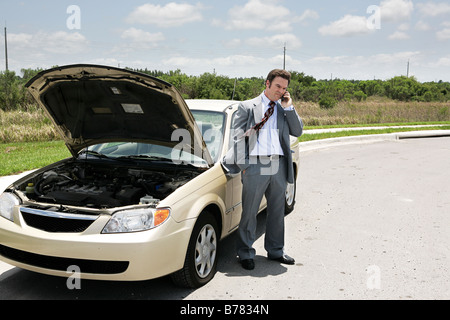 Un homme avec un pneu à plat sur le téléphone avec le club auto Banque D'Images