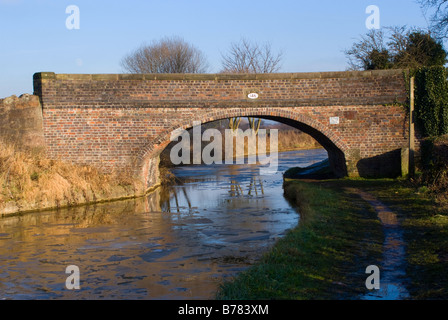 Un ancien pont routier sur un canal de Trent et Mersey gelés par une froide journée d'hiver ensoleillée près de Alsager Cheshire England UK Banque D'Images