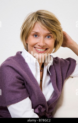 Femme assise sur un canapé Banque D'Images