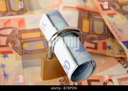 Un rouleau de 20 euro note verrouillé dans un cadenas,sur un fond de 50 euros. Symbolisant la sécurité financière. Banque D'Images