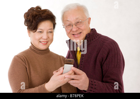 Couple de personnes âgées à la recherche au téléphone mobile et sourire heureux Banque D'Images