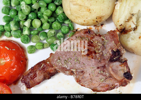 Longe d'agneau grillé au romarin hacher,pomme de terre au four, tomates et pois. Macro Banque D'Images