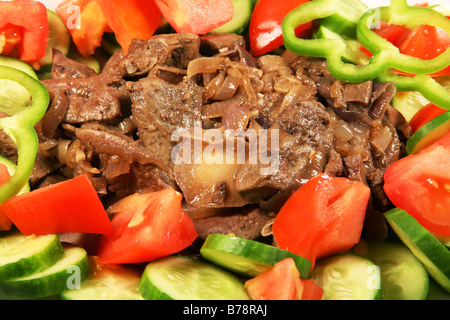 Le foie et les oignons frits sur un plat de service, garnir de salade. Banque D'Images