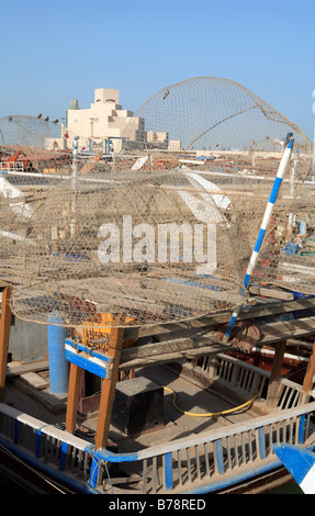 Le Musée d'art islamique à Doha, Qatar,vu à travers les pièges à poissons traditionnels empilés sur un vieux bateau dans le port adjacent. Banque D'Images