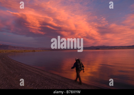 Un homme de la randonnée le long de la rive du lac Mono avec de l'eau et les nuages reflétant en Californie Banque D'Images