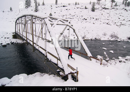 Un homme court à travers un tressel pont sur un jour de neige près de Truckee en Californie Banque D'Images