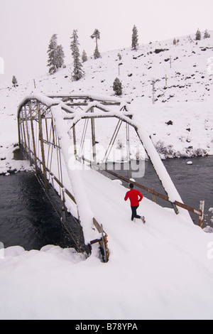 Un homme court à travers un tressel pont sur un jour de neige près de Truckee en Californie Banque D'Images