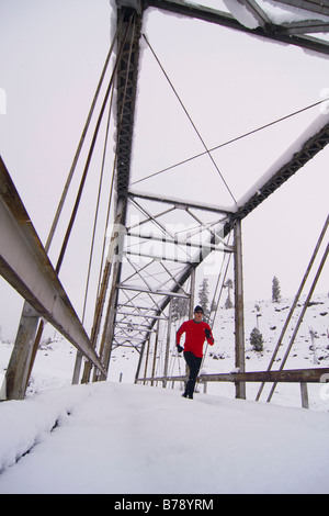 Un homme court à travers un tressel pont sur un jour de neige près de Truckee en Californie Banque D'Images