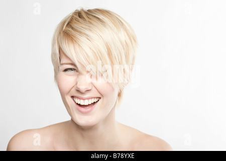 Jeune femme blonde aux cheveux courts rire dans l'appareil photo Banque D'Images