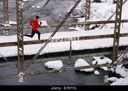 Un homme court à travers un tressel pont sur un jour de neige près de Truckee en Californie Banque D'Images