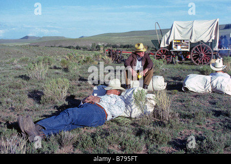Cowboys sur un transport de bétail répéter dans leurs paquetages set cowboy et attendez que le cuisinier à préparer le petit-déjeuner dans le Chuck Wagon, le nord du Nouveau Mexique. Banque D'Images